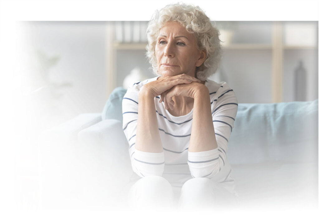 older woman sitting and thinking with her chin resting on her hands